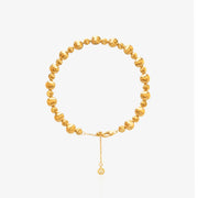 Gold Bead Bracelet — alternating large smooth mirror-polished spheres and small threaded spiral spacer beads on elastic cord, with diamond-accented tag at lobster clasp extension, 18K gold plated, worn on wrist with white sleeve