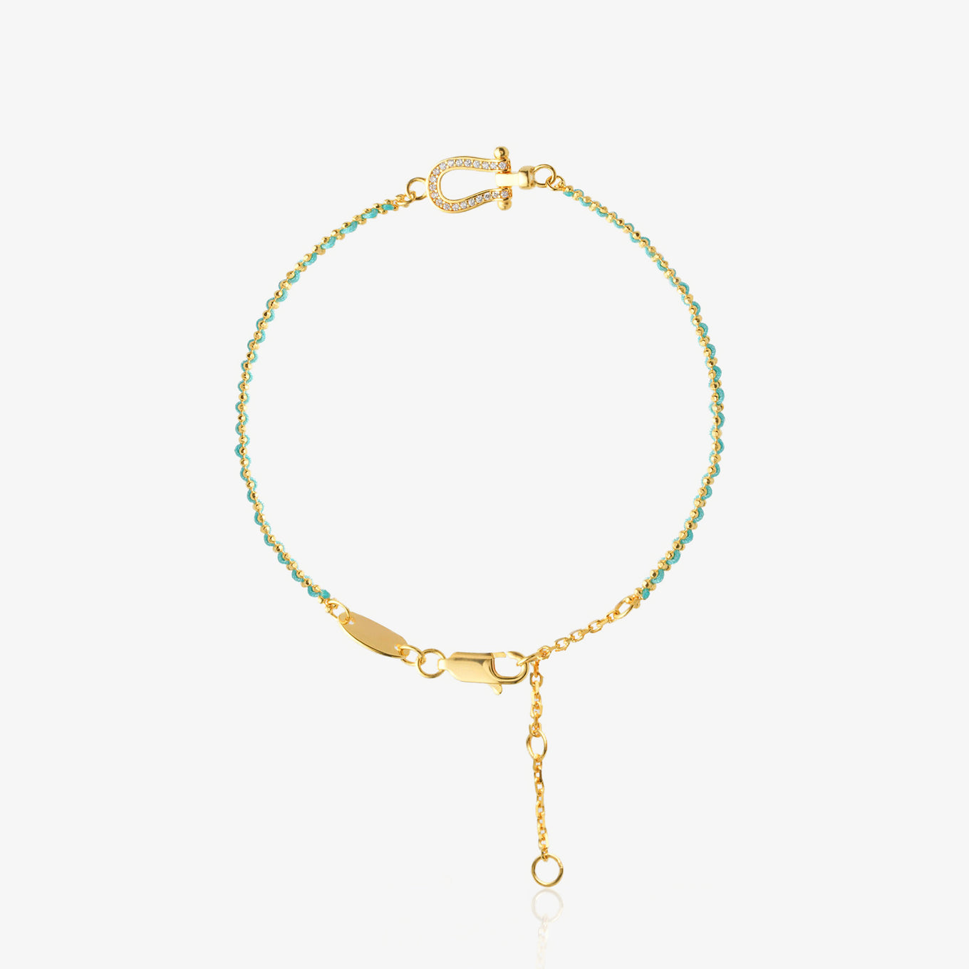 Dainty two-tone bracelet — mint green faceted bead section meets gold O-chain with diamond-encrusted U-shaped horseshoe charm at center, 18K gold-plated, worn on wrist with white sleeve, minimalist vacation style