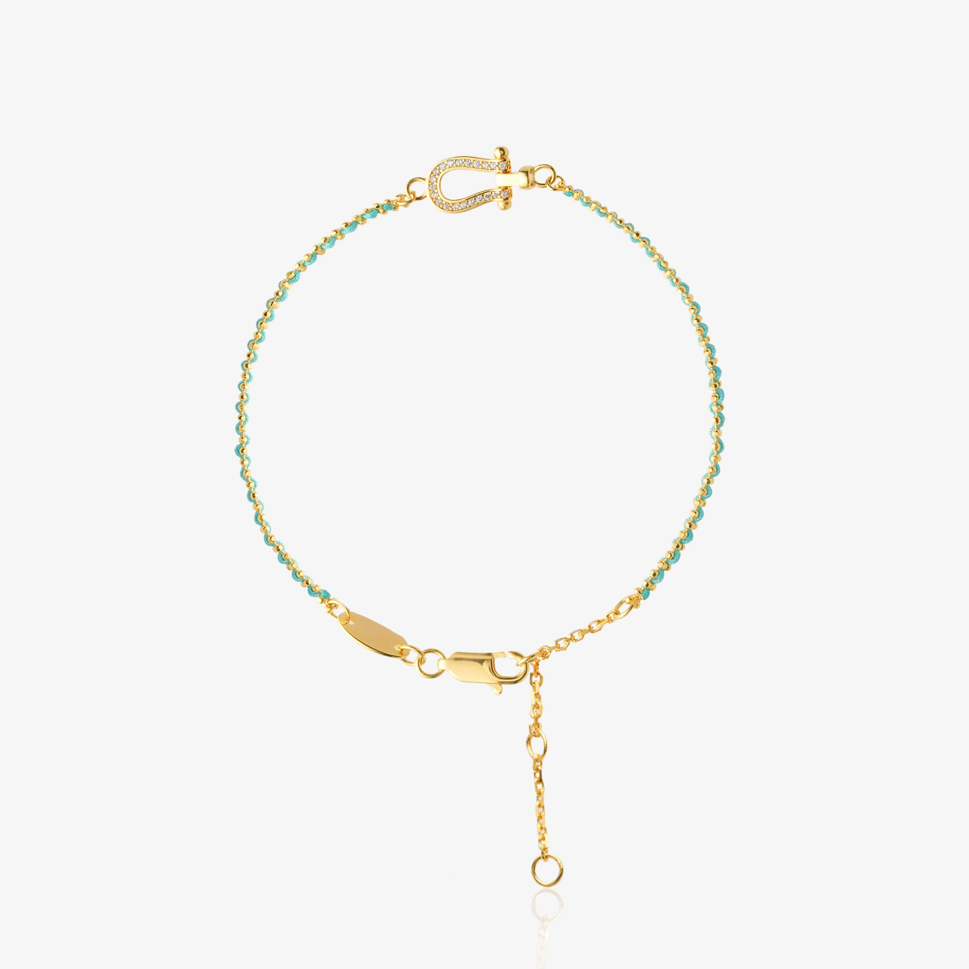Dainty two-tone bracelet — mint green faceted bead section meets gold O-chain with diamond-encrusted U-shaped horseshoe charm at center, 18K gold-plated, worn on wrist with white sleeve, minimalist vacation style
