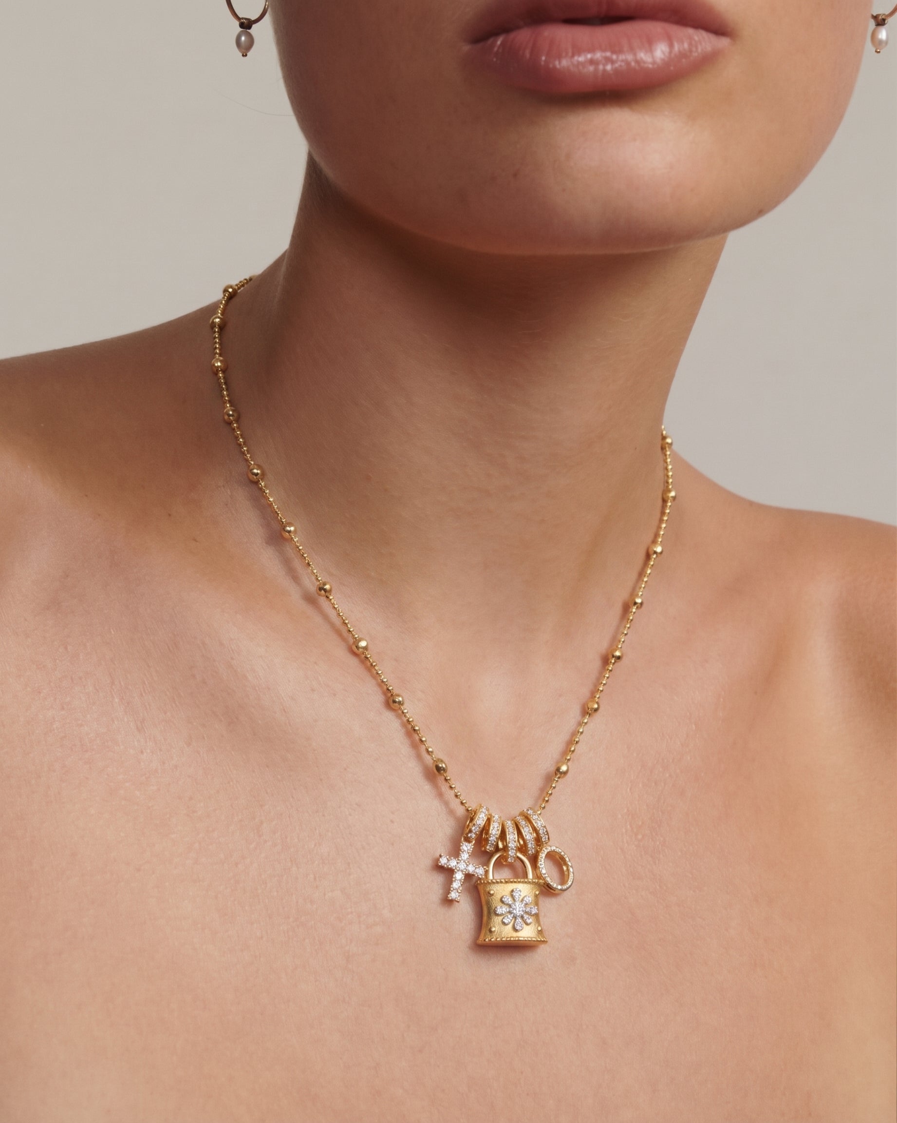 Gold Lock Charm Necklace flat lay detail — full 45+5cm beaded chain with all 5 pendants visible: padlock, marquise charm, star charm, 3 graduated baguette tassels, brushed satin finish on lock body, 8.86g