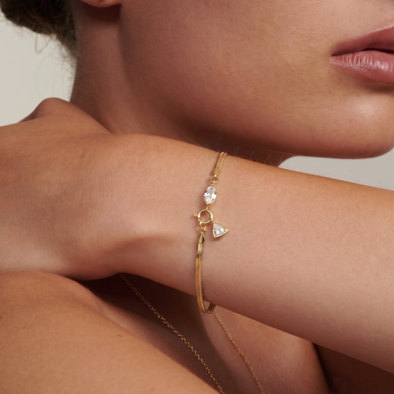 Gold Herringbone Bracelet close-up — marquise-cut lab diamond accent and bezel-set triangle pendant detail on satin-brushed flat chain, minimalist geometric design