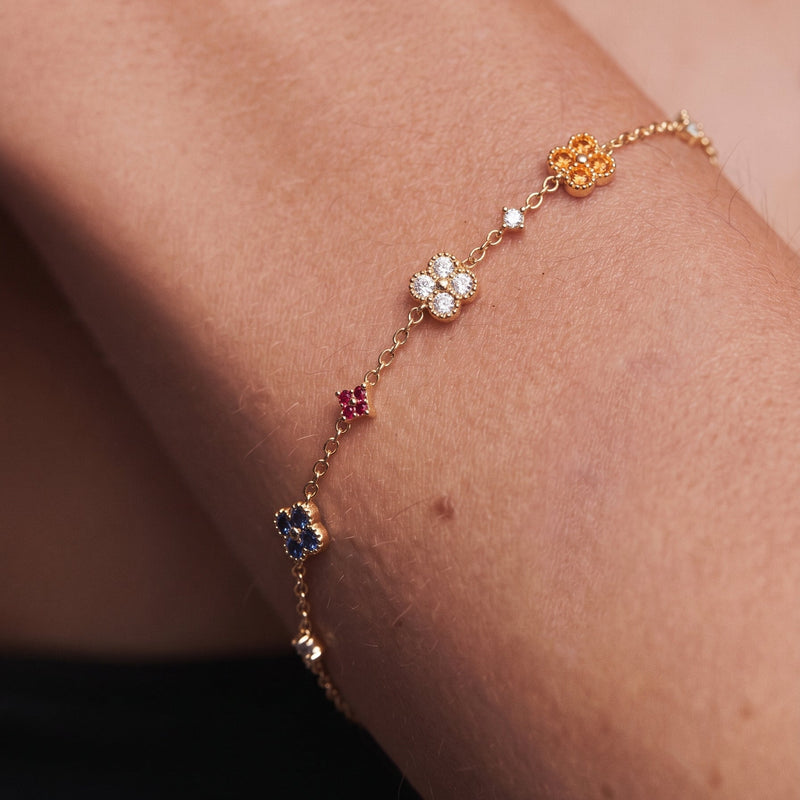 Multi-Color Clover Bracelet close-up detail — individual four-leaf clover charm with bezel-set colored stones and micro star accent on fine gold cable chain, showing pastel color contrast