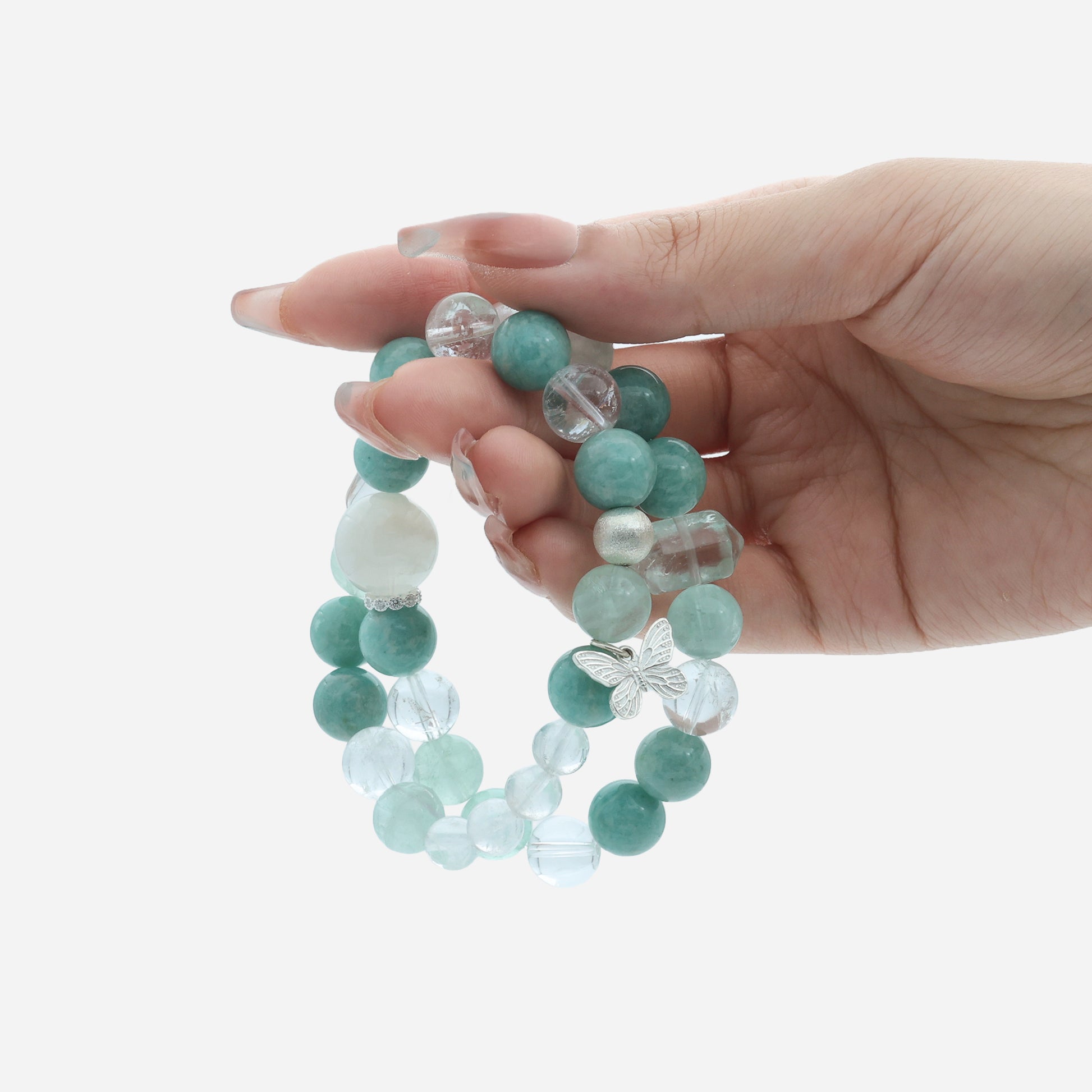 Hand holding the Spirit Flutter gemstone bracelet highlighting the unique Snow Ghost Quartz and Green Quartz pillar stones