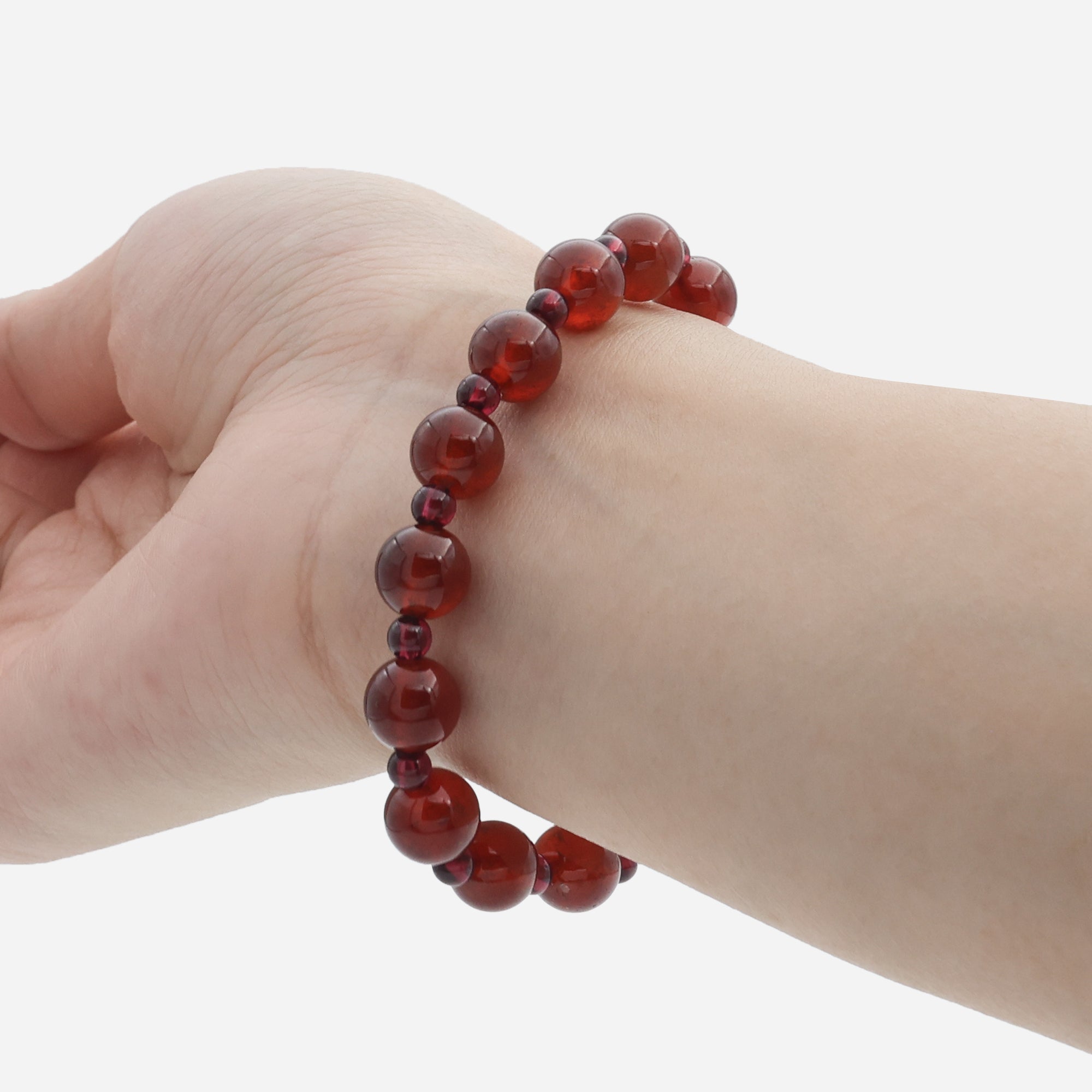 Close-up of natural red garnet beaded bracelet in natural light showing genuine stone inclusions and faceted quartz center bead detail