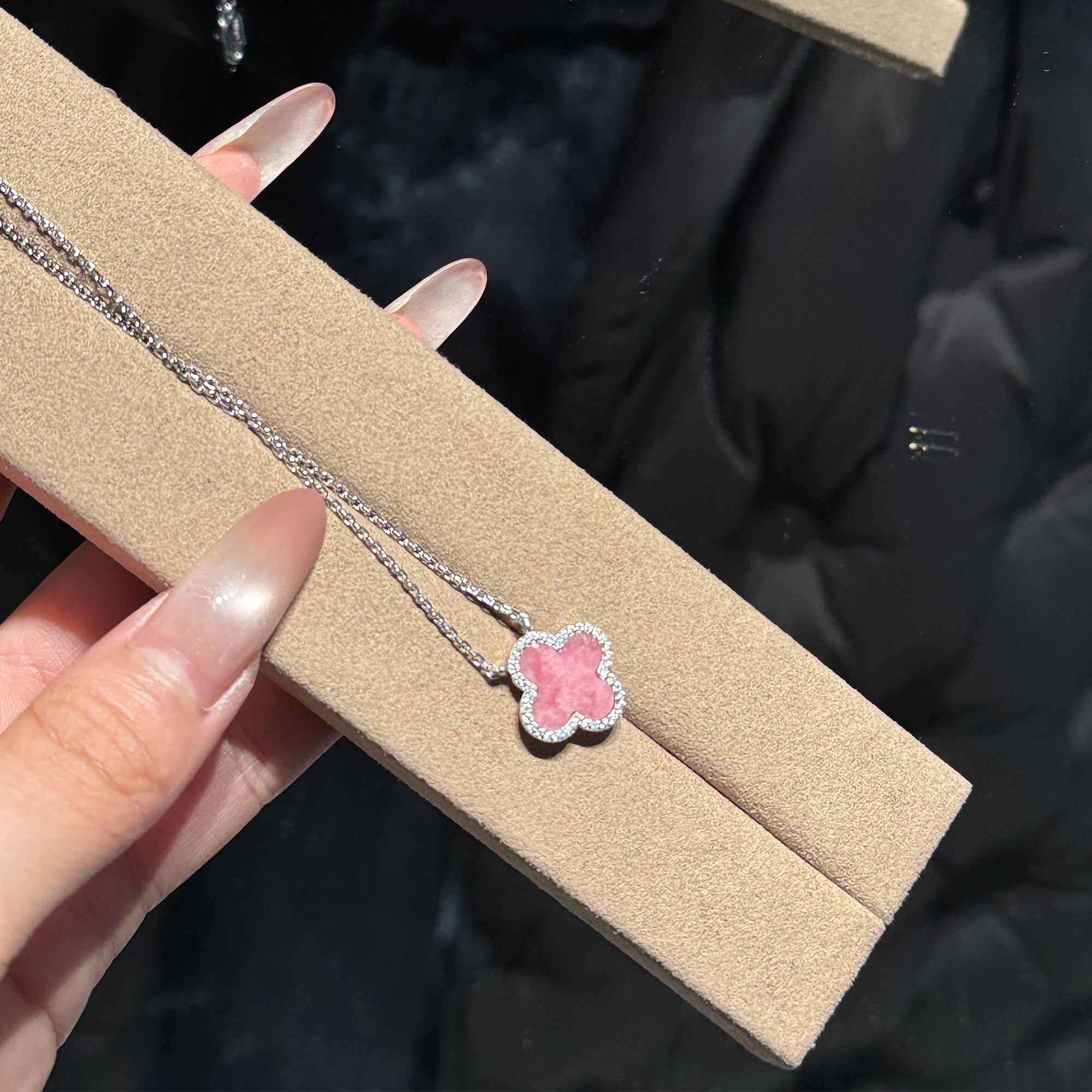 Lifestyle view of the reversible pink petal clover necklace displaying the iridescent mother of pearl glow and