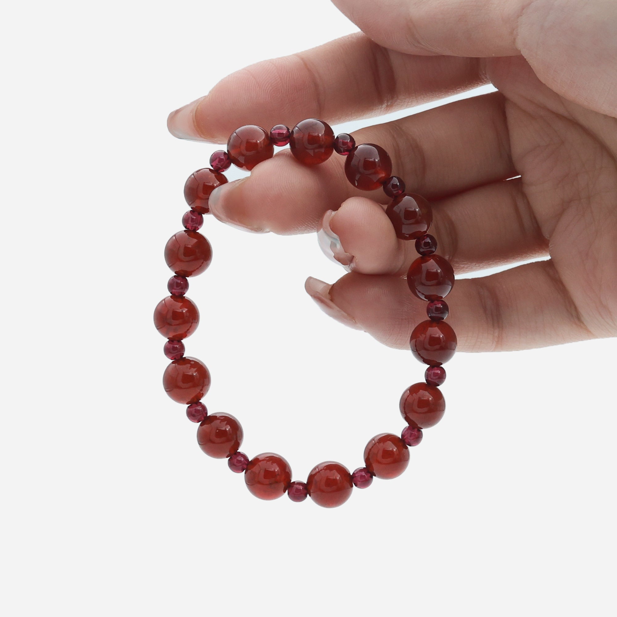 Close-up of hand holding the natural Garnet bracelet, highlighting the contrast between the 8mm and 4mm beads.