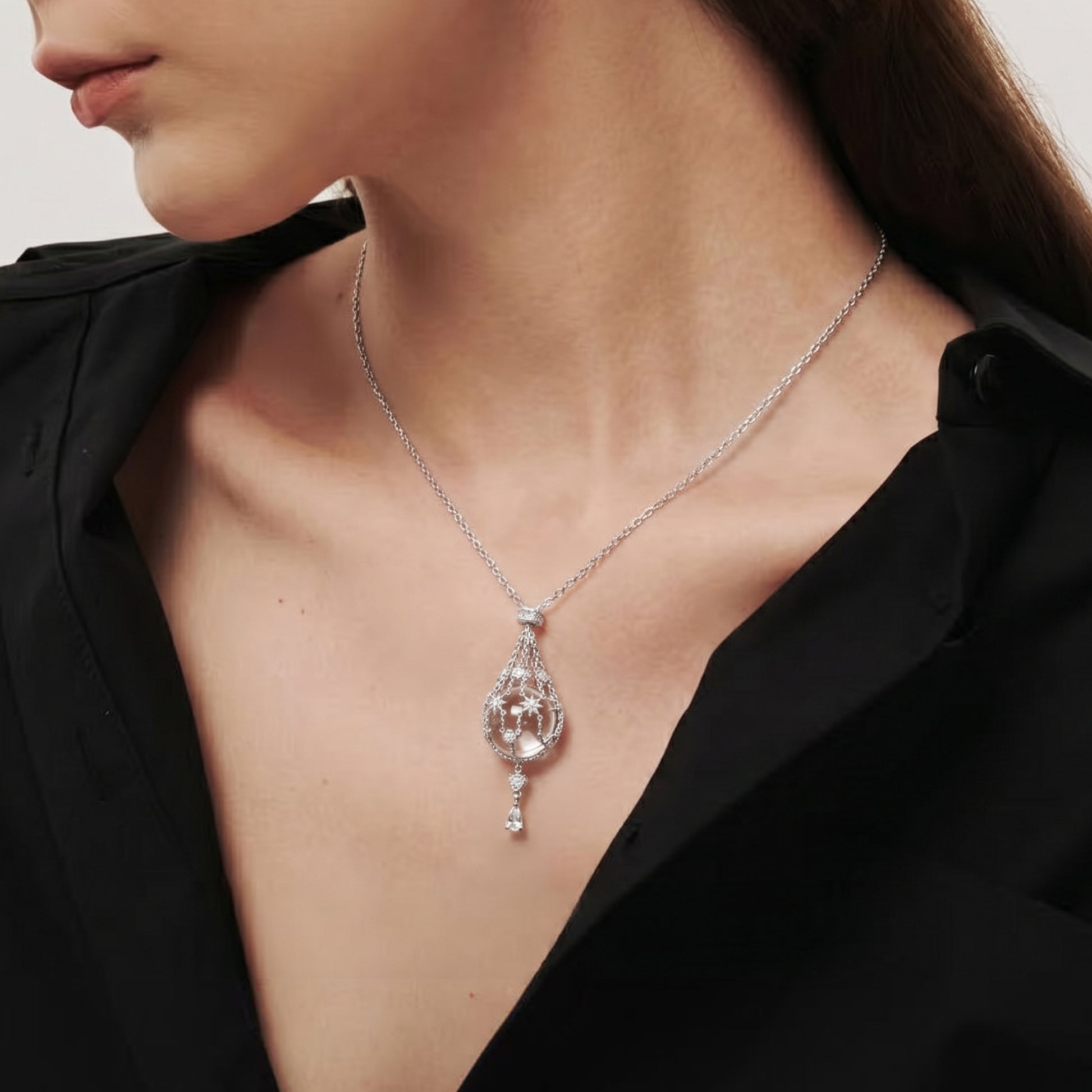 Lifestyle view of the Stellar Pavilion cage necklace on a model, showcasing the elegant drop and light-refracting crystal.